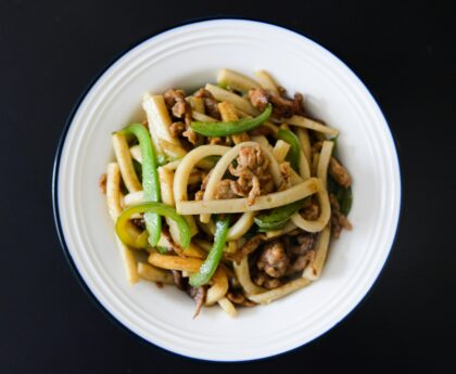 Delicious stir-fried udon noodles with pork and fresh vegetables on a plate.