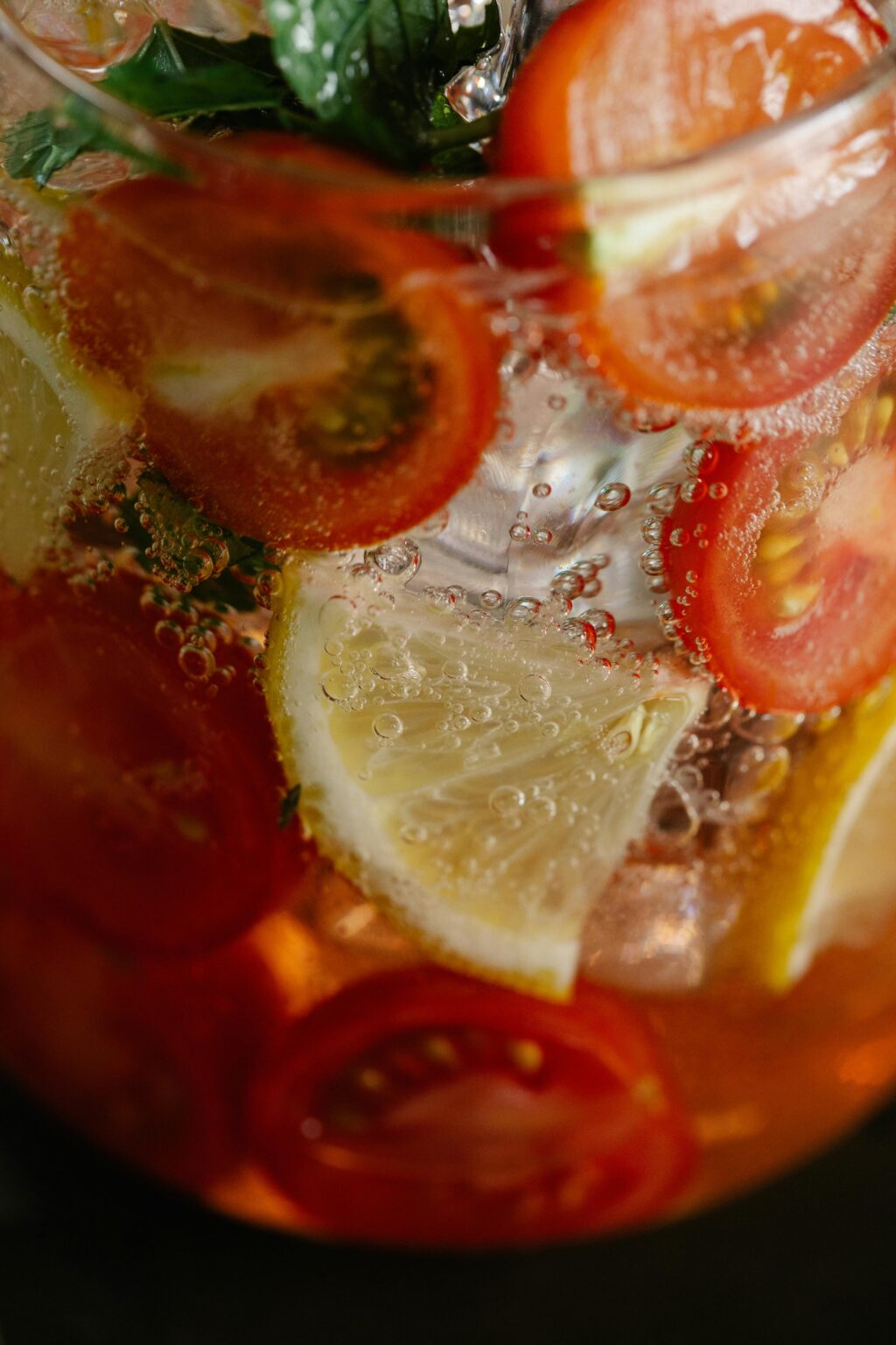 Close-up view of a refreshing citrus drink with sliced lemon and cherry tomatoes.
